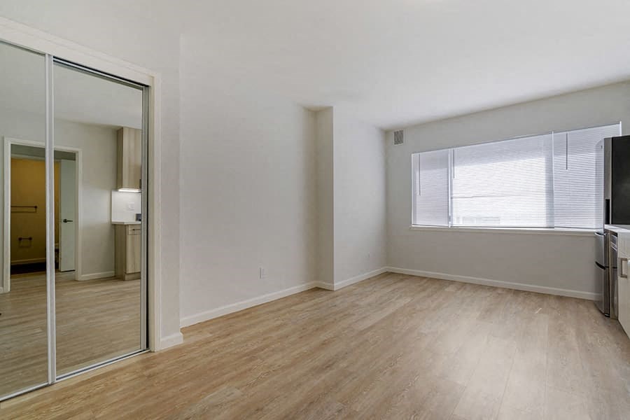 a bedroom with a large window and hardwood floors