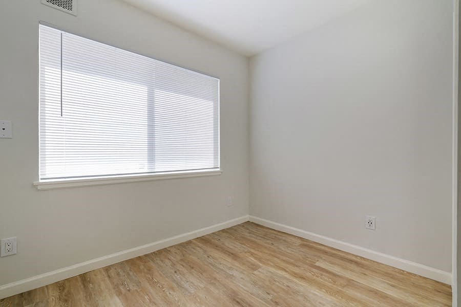 an empty room with a large window and wooden floors