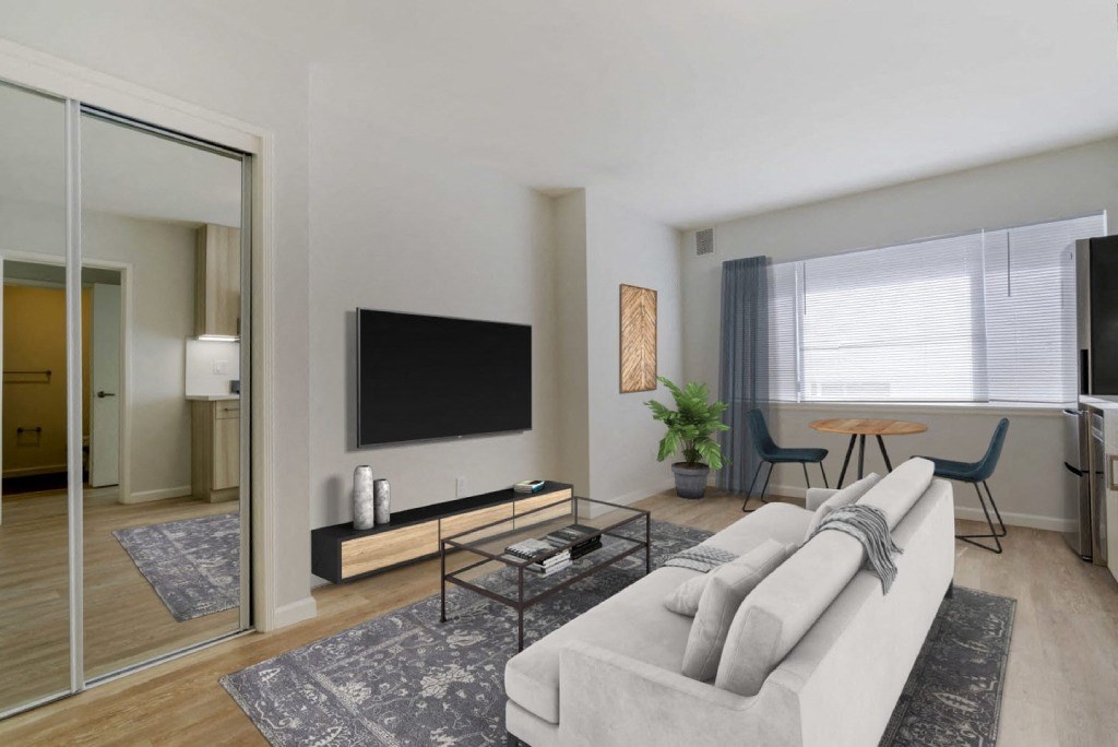 a living room with a couch a coffee table and a tv on the wall