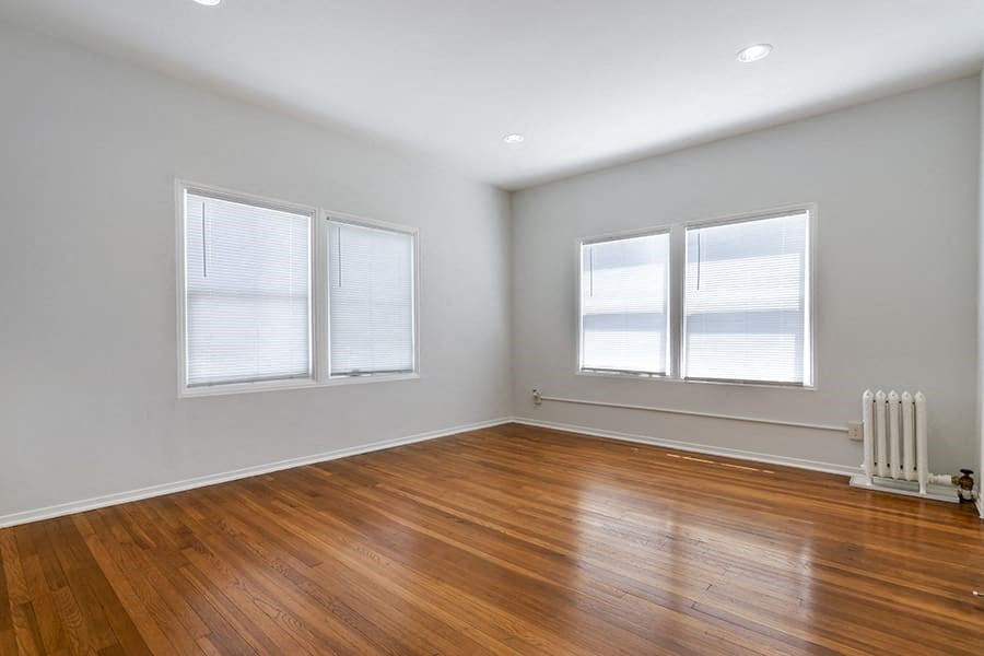 an empty room with a wood floor and three windows