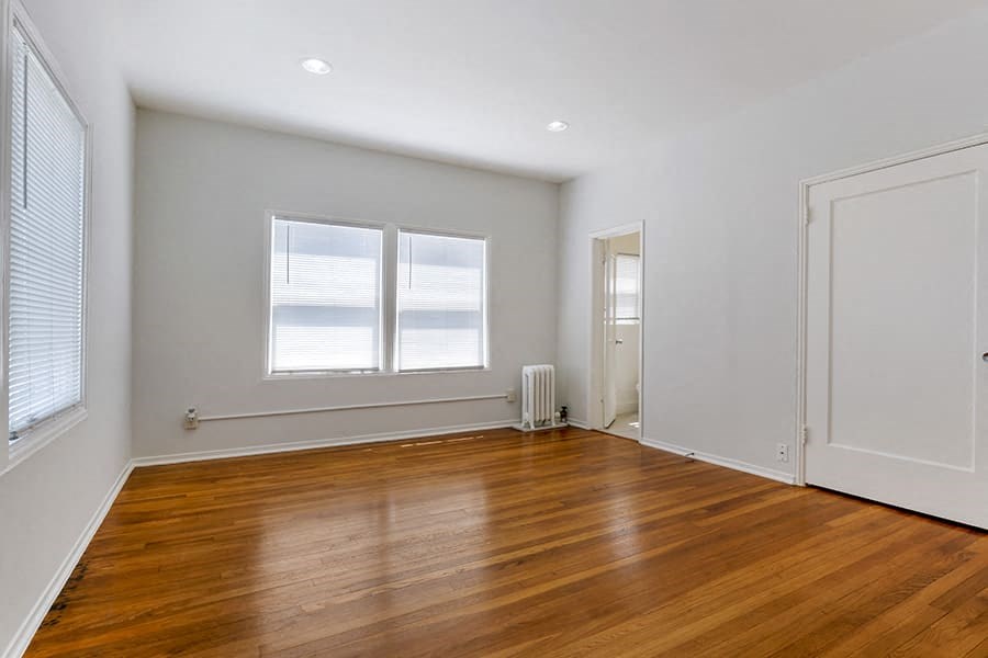 a room with a hardwood floor and two windows