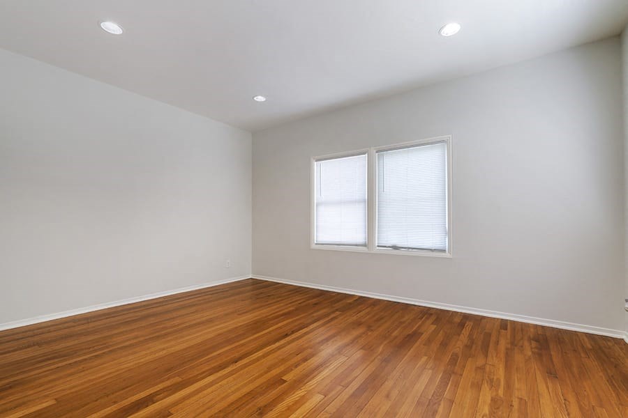 an empty room with a hardwood floor and two windows