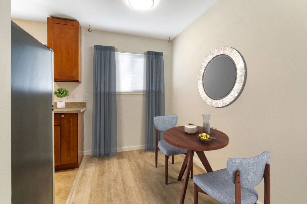 a dining area with a small table and chairs next to a kitchen with a stainless steel refrigerator