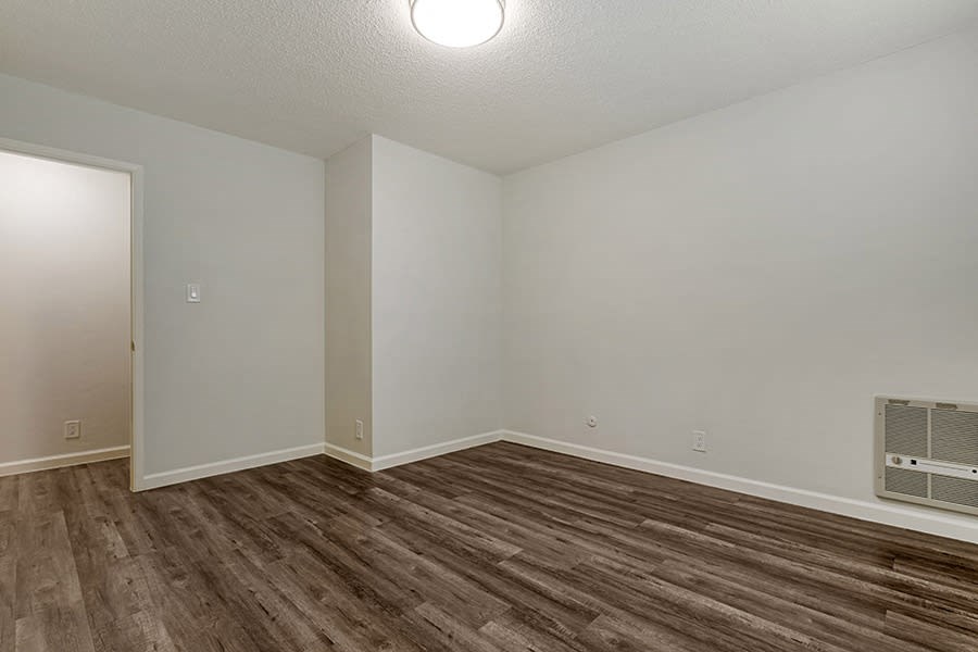 a bedroom with hardwood flooring and white walls