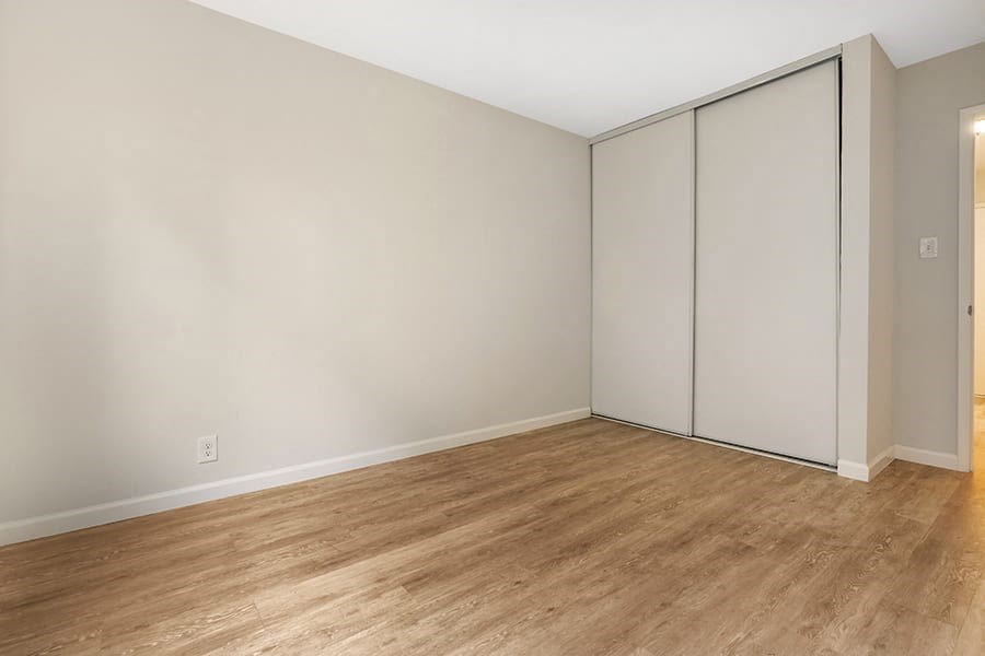 a bedroom with white walls and a wooden floor