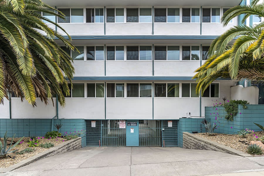 an image of the front of a building with palm trees in front of it