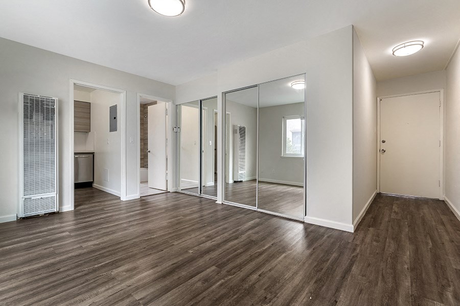 a bedroom with hardwood floors and a large mirror