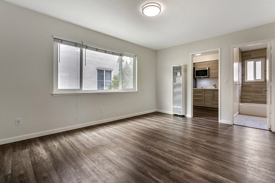 a bedroom with a large window and hardwood floors
