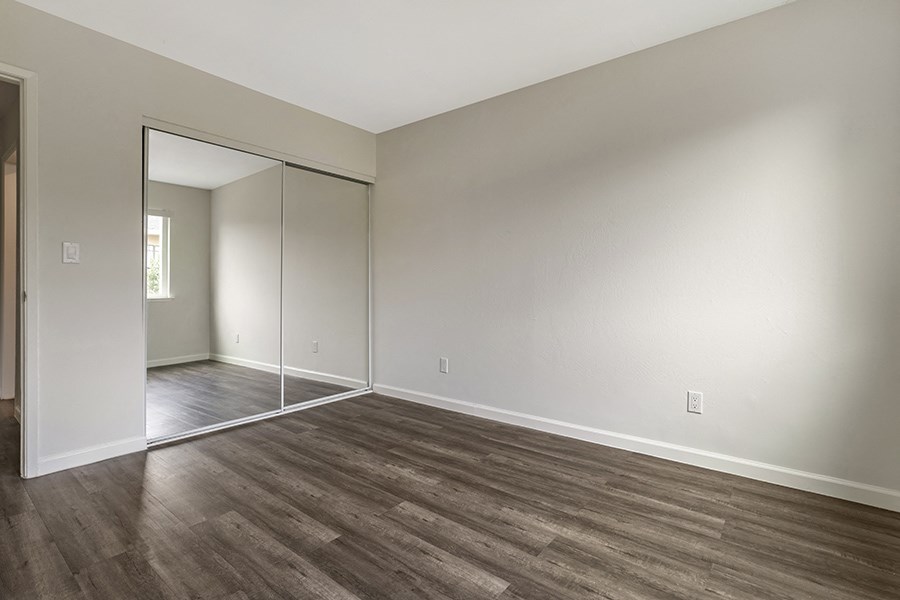 a bedroom with hardwood floors and a large mirror