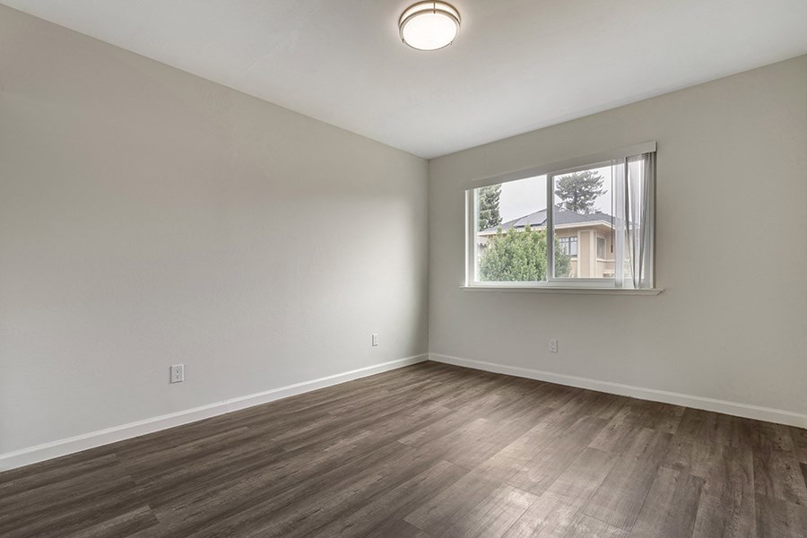 a bedroom with hardwood floors and a large window