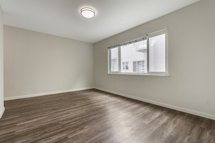 a bedroom with hardwood floors and a large window