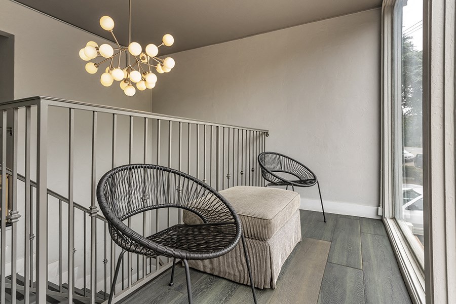 a seating area with a chair and ottoman and a chandelier