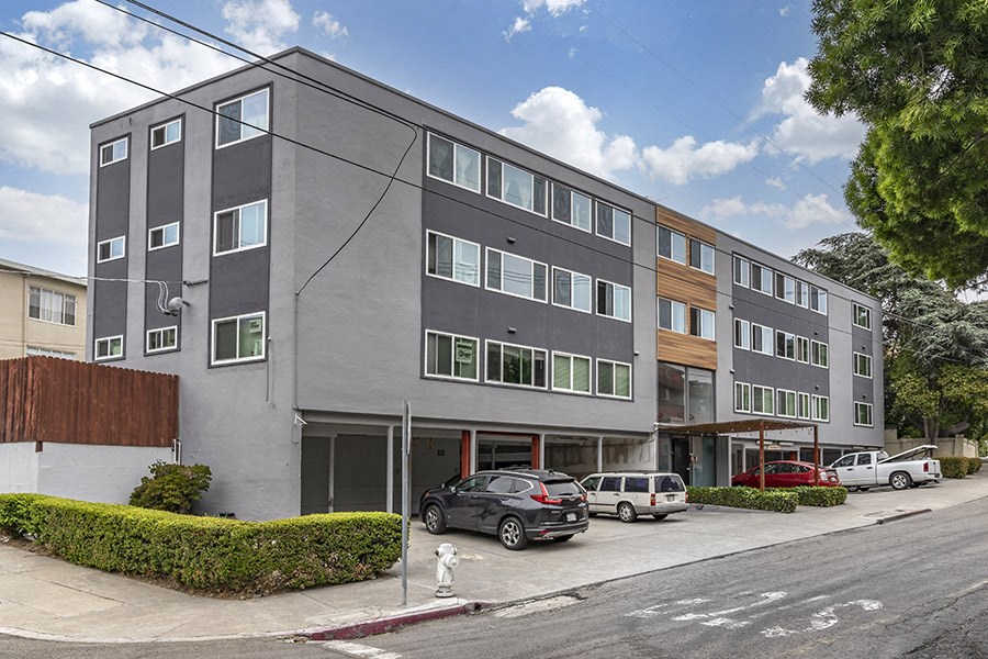 a large grey apartment building with cars parked in front of it
