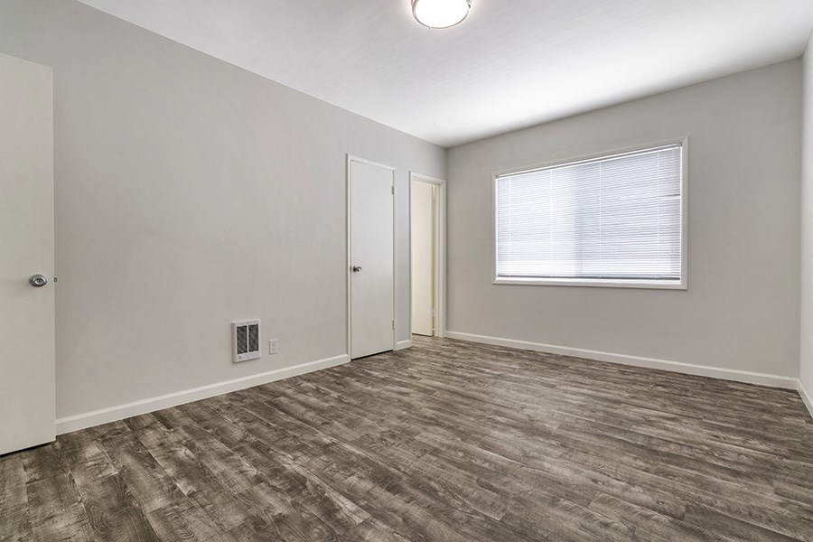 a bedroom with hardwood floors and grey walls