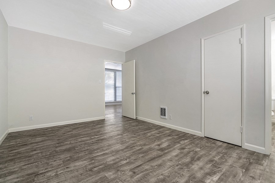 a bedroom with hardwood floors and white walls