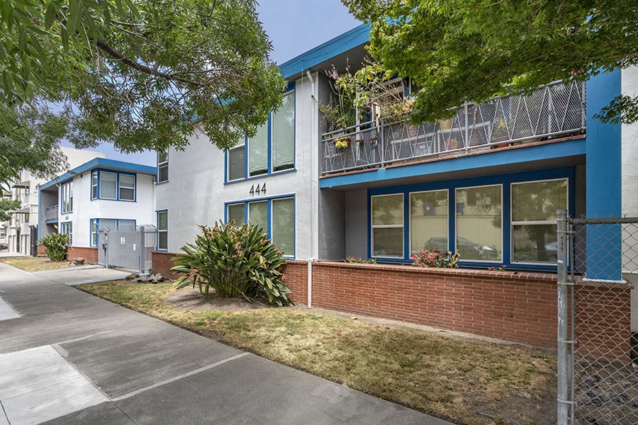 a building with a blue and white facade and a sidewalk in front of it