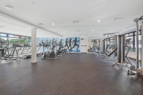 A gym with treadmills, elliptical machines, and other cardio equipment at Wilshire Valencia Apartment, Los Angeles, California
