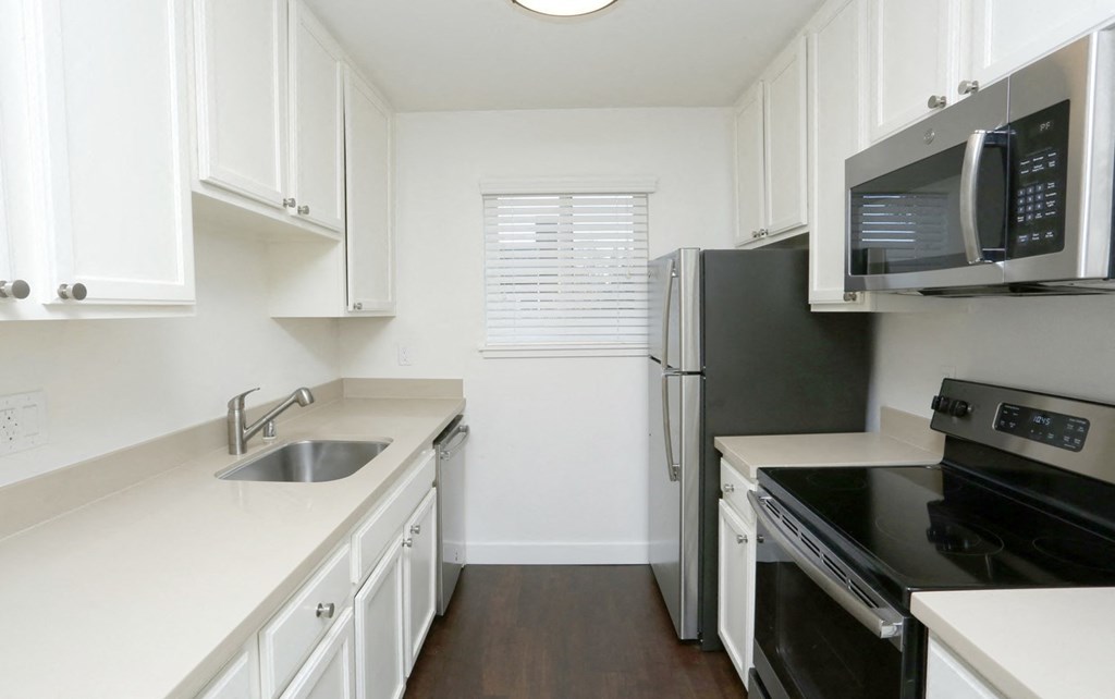 A kitchen with black appliances and white cabinets.