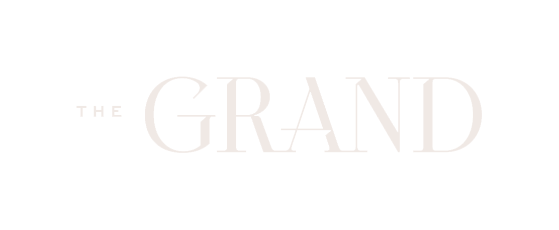 The image shows a logo with the words "THE GRAND" in white text on a black background.