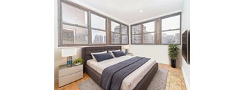 A bedroom with a large bed and a window overlooking a cityscape.