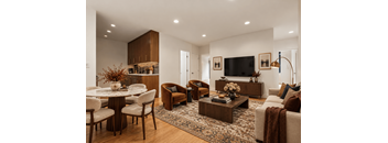A living room with a large sofa, a coffee table, and a TV on the wall.