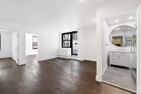 A spacious room with wooden floors and white walls.