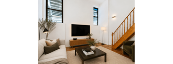 A living room with a white couch, a wooden coffee table, and a flat screen TV mounted on the wall.