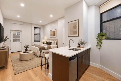 A modern kitchen with a large island and a bedroom in the background.