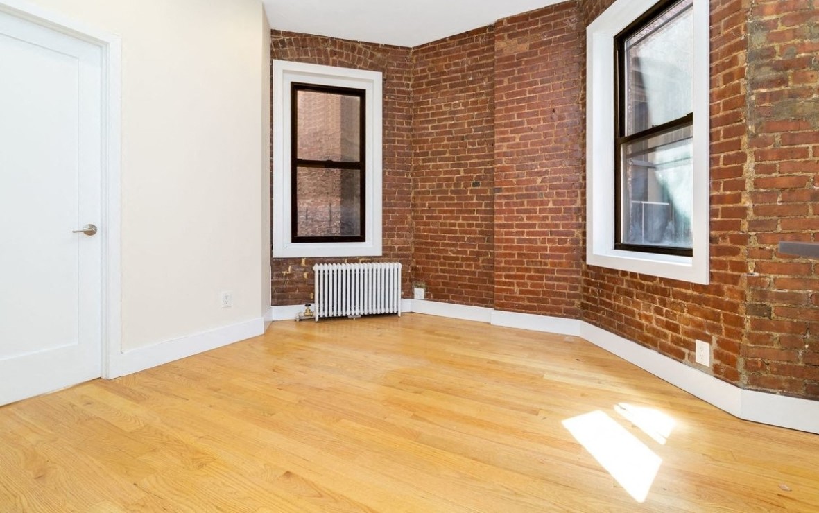 A room with a white door, a window with a white frame, and a brick wall.