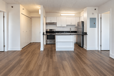 A kitchen with white cabinets and a black fridge.