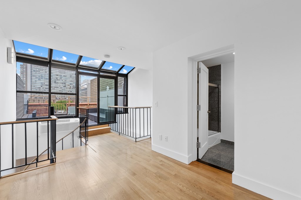 A room with a white wall and a door leading to a balcony.