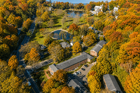 A small building is surrounded by trees with autumn leaves.
