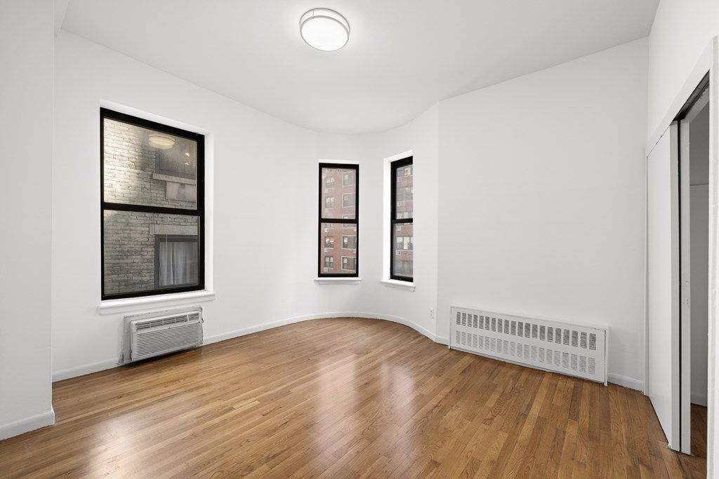 A room with wooden floors and two framed pictures on the wall.