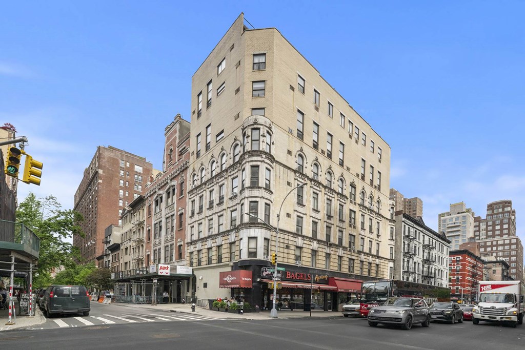 A street view of a city with a large building in the middle and cars on the road.