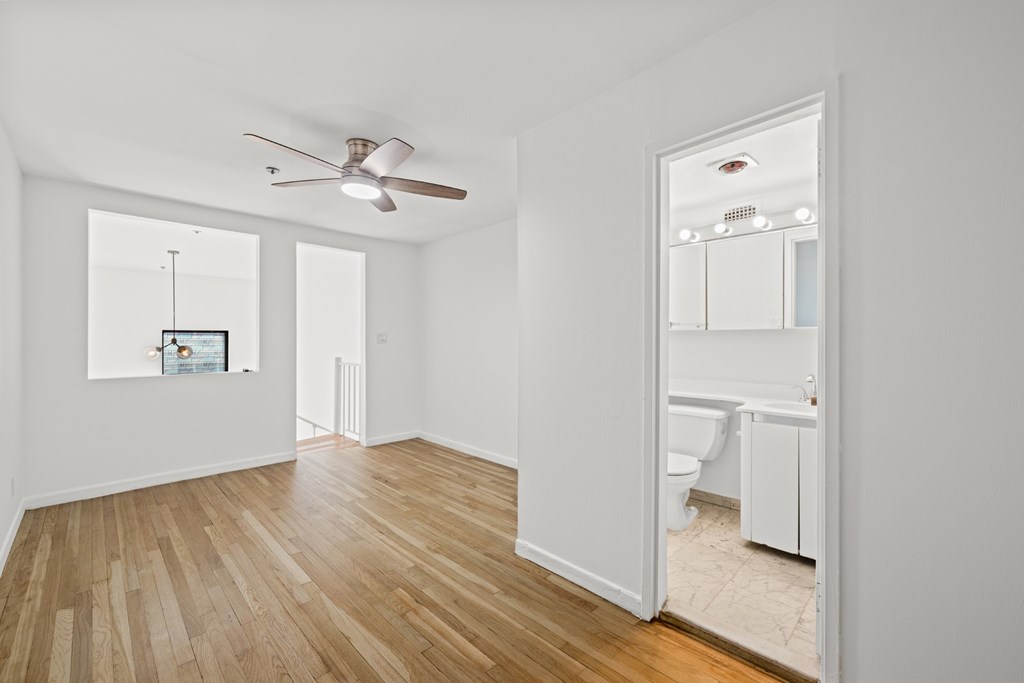 A room with a ceiling fan and a mirror on the wall.