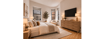A bedroom with a large bed, a dresser, and a flat-screen TV mounted on the wall.