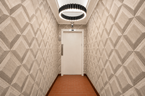 A hallway with a white door and a light hanging from the ceiling.