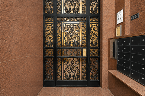 A black and gold patterned door with a sign above it.