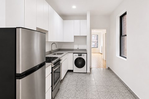 A kitchen with white cabinets and a black fridge.
