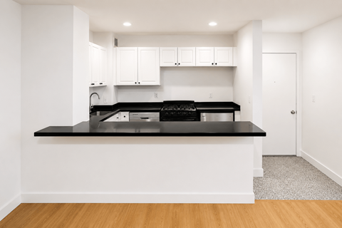 A modern kitchen with white cabinets and black countertops.