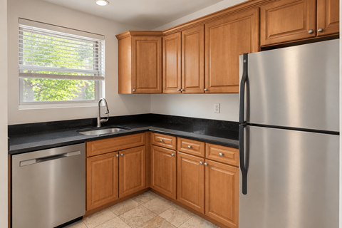 A kitchen with wooden cabinets and a stainless steel refrigerator.