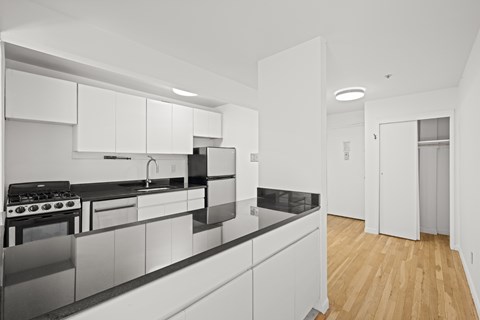 A modern kitchen with white cabinets and black countertops.