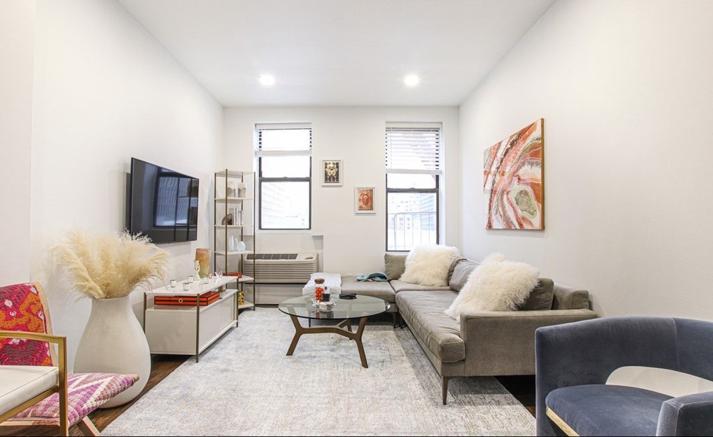 A living room with a grey couch, a white vase, a red chair, and a painting on the wall.
