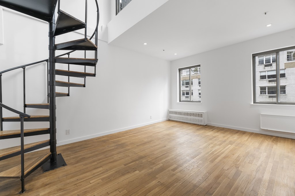 A room with a spiral staircase and wooden flooring.