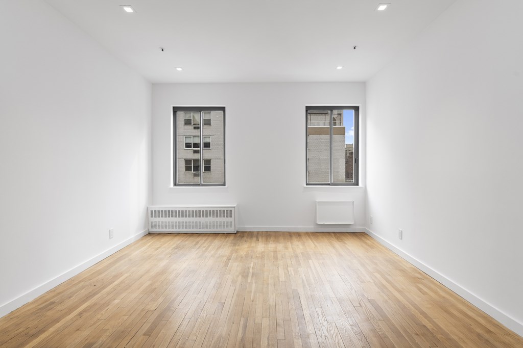 A room with wooden floors and two windows.
