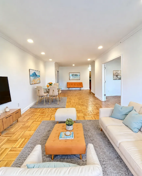A living room with a white couch and a wooden floor.