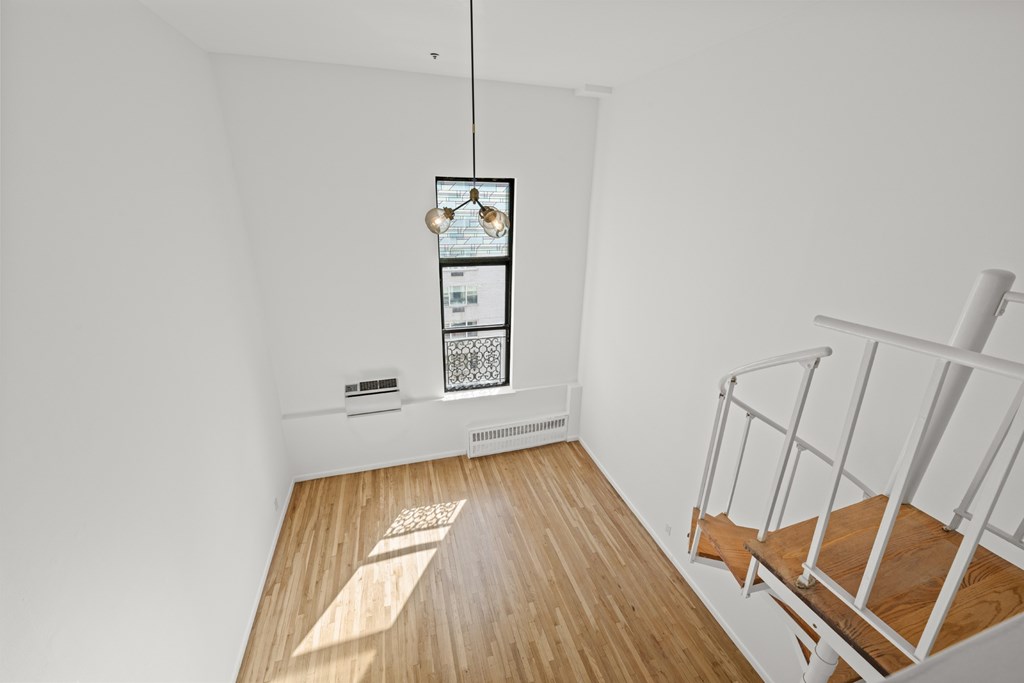 A room with a wooden floor and a staircase.