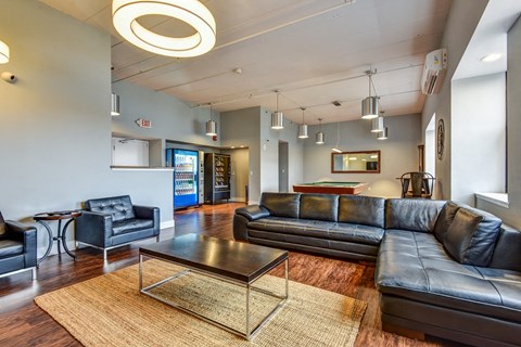 A living room with a black leather couch and a glass coffee table.