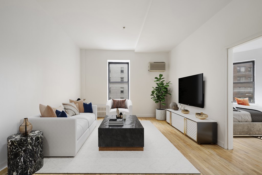 A modern living room with a white sofa, a black coffee table, and a flat-screen TV.
