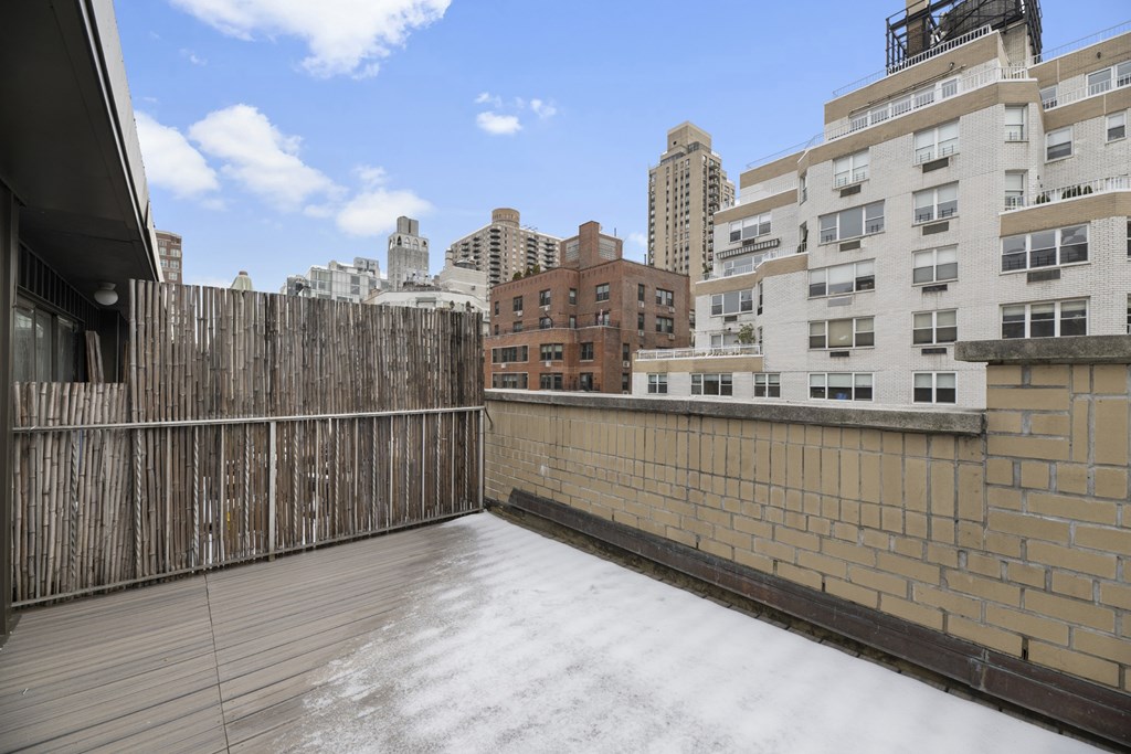 A wooden fence surrounds a snow-covered deck.